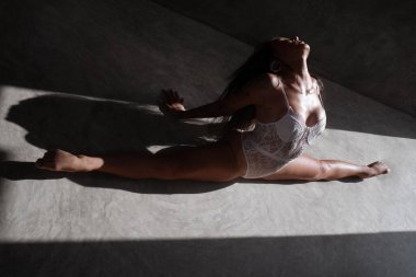 Beyaz dantelli iç çamaşırlarıyla güzel bir akrobatik stüdyoda beton zeminde ikiye bölünüyor.