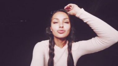 Şirin ve seksi esmer kız pembe uzun kollu bluz ve külotlu çorap giyiyor ve güneş gözlükleri takıyor dans ediyor, gülümsüyor, yaz akşamları flört ediyor - yavaş çekimde video.