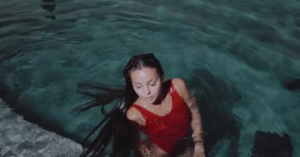 美しいブルネットの女性の肖像画で赤い水着姿で屋外プール ビデオでスローモーション — ストック動画