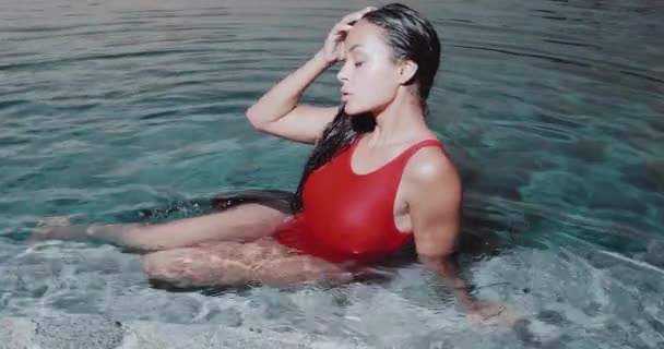 美しいブルネットの女性の肖像画で赤い水着姿で屋外プール ビデオでスローモーション — ストック動画