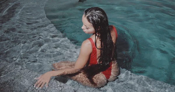 美しいですブルネット女性で赤水着Posingで屋外プールで夜 — ストック写真