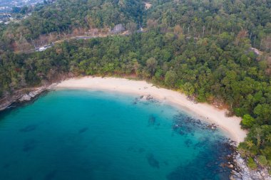 Turkuaz deniz suyu ve kayalarla tropikal boş kumsalın hava aracı görüntüsü.