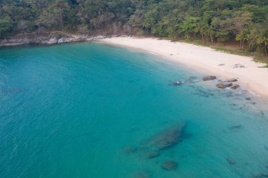 Turkuaz deniz suyu ve kayalarla tropikal boş kumsalın hava aracı görüntüsü.