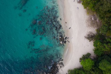 Turkuaz deniz suyu ve kayalarla tropikal boş kumsalın hava aracı görüntüsü.