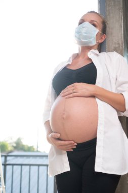Grip ve virüslere karşı koruyucu maskeli hamile bir kadın. Sağlık hizmetleri kavramı