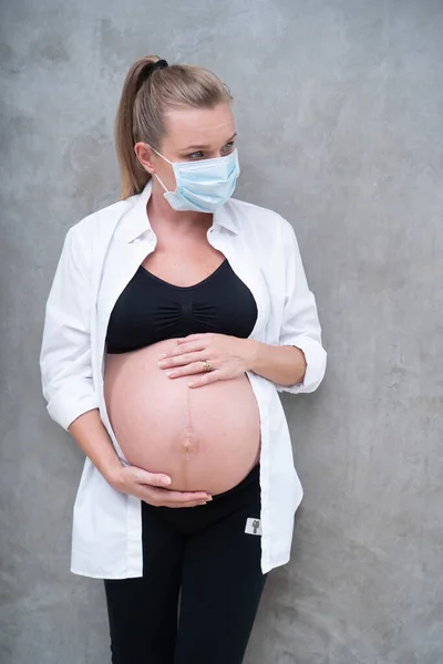 灰色の壁の背景にインフルエンザやウイルスに対する保護マスクの妊婦 医療の概念 — ストック写真
