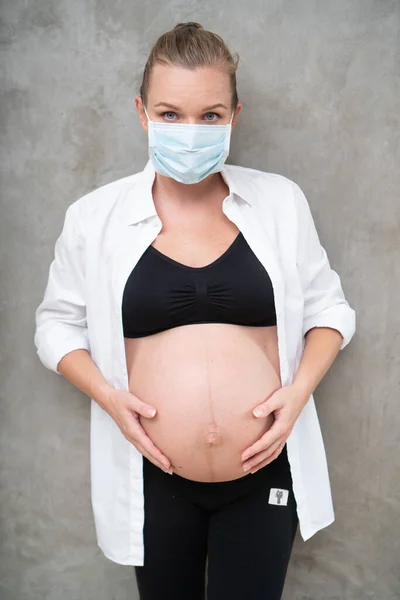 身披防毒面具的孕妇在灰墙背景下抵御流感和病毒 保健概念 — 图库照片