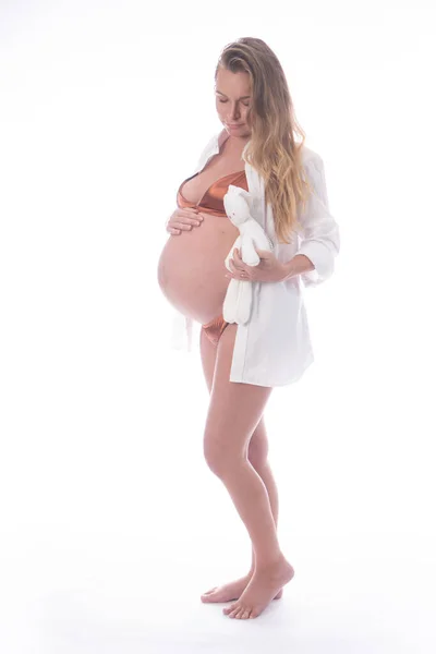 白い背景の上にウサギのおもちゃで立ってかなり妊娠中の女性 産前概念 — ストック写真