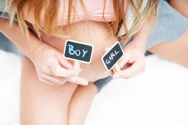 自宅でベッドに座っている間に書かれた男の子と女の子とミニ黒板を持っている妊婦の作物のイメージ 新しい生活と家族計画の概念 — ストック写真