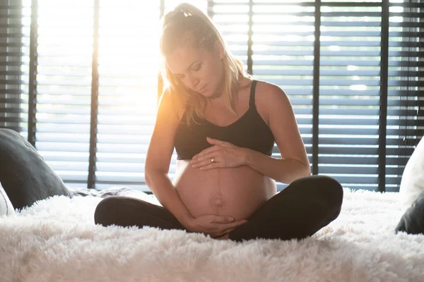 Pěkná Těhotná Žena Černých Legínách Podprsence Drží Břicho Zatímco Odpočívá — Stock fotografie