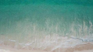 Tropik plaj drone manzarası, dalgaların üst görüntüsü tropikal beyaz kumsalda kırılıyor..