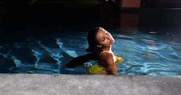 晚上在游泳池里穿着黄色比基尼的性感女人 — 图库视频影像