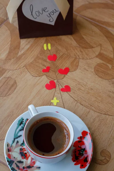 Чашка кофе с подарком с сердечками на фоне цветка — стоковое фото