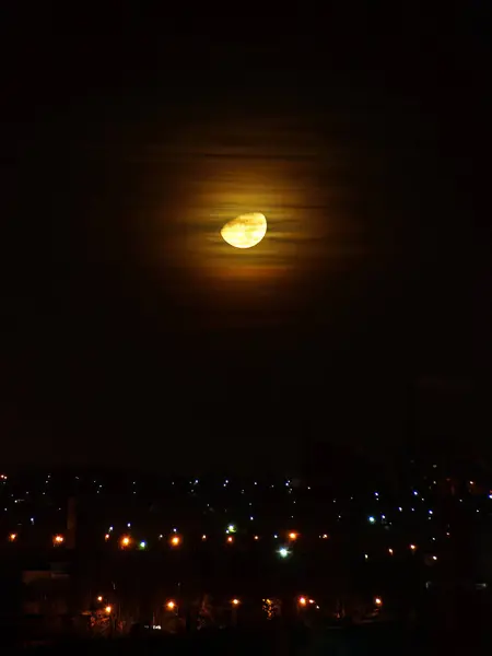 Lua grande em nuvens sobre a cidade da noite . — Fotografia de Stock