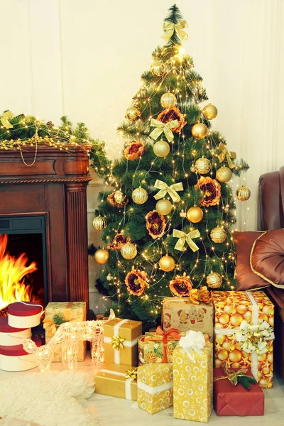 Christmas fir-tree, golden christmas decorations and gifts near fireplace in interior. — Stock Photo, Image
