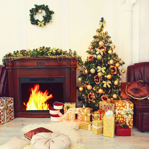 Abeto de Natal colorido, decorações de Natal douradas e presentes perto da lareira no interior . — Fotografia de Stock