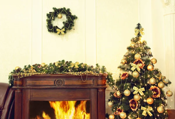Julgran med gyllene julpynt nära öppen spis i interiören. — Stockfoto