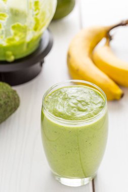 Kesinlikle lezzetli yeşil avokado Shake veya güler yüzlü, taze avokado ile yapılmış şaşırtıcı muz, limon suyu ve Non süt (badem veya Hindistan cevizi) süt ışık Beyaz ahşap arka plan, Raw Food, Vegan içki, Vegan gıda anlayışı, yakın çekim