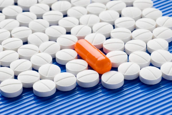 Píldoras Blancas Sobre Fondo Azul Que Rodea Una Píldora Diferente — Foto de Stock