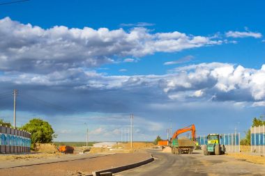 Paletli ekskavatör kova yüksek hızlı bypass yol kazma. Çalışma asfalt finişer ve vücut kamyonla. Ağır makine ekipman Kazı için endüstriyel inşaat İnşaat
