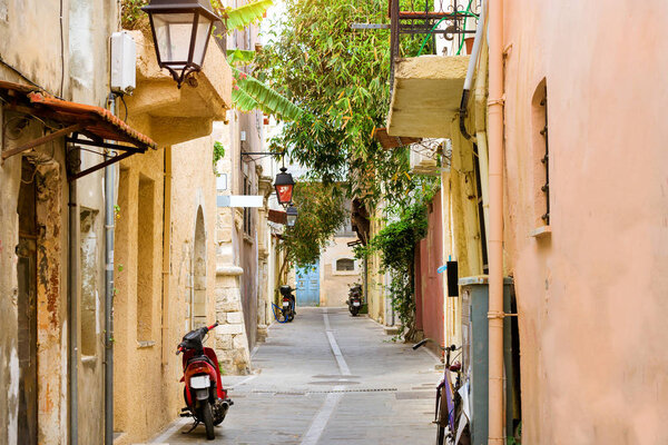 Walk around the old resort town Rethymno in Greece. Architecture and Mediterranean attractions on island Crete. Narrow touristic street with parked scooters