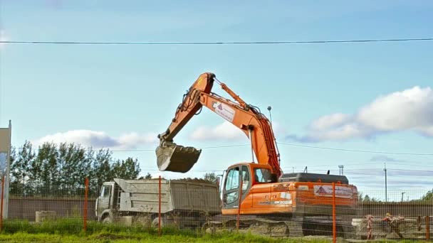 Excavator bucket loads heavy truck with ground — Stock Video