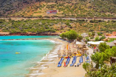 Güneşli kumlu Livadi beach için yapılan deniz tatil köyü Bali Körfezi. Dağ, kıyı, görünümlerini dalgalar tarafından yıkanmış ve şezlong şemsiye ile nerede turist güneşlenme. Bali, Rethymno, Crete, Yunanistan