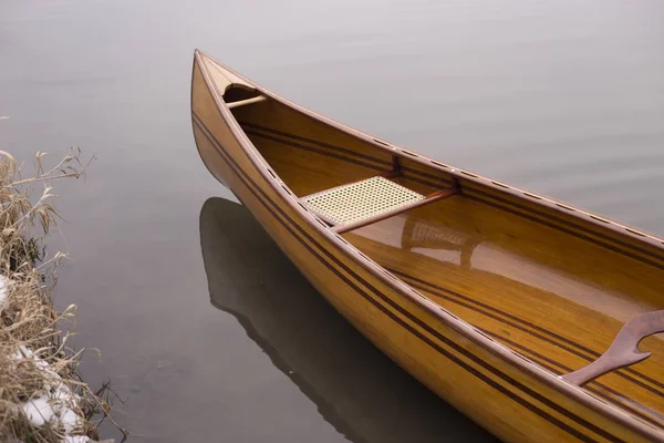 Nova canoa flutuando na água calma no pôr do sol de inverno — Fotografia de Stock