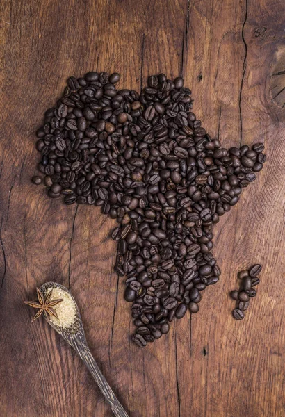 Grains de café torréfiés disposés en forme d'Afrique sur du vieux bois — Photo