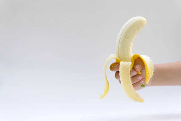 Το χέρι της γυναίκας κατέχει μια μπανάνα, είναι απομονωμένα σε λευκό λεμονάτα — Φωτογραφία Αρχείου
