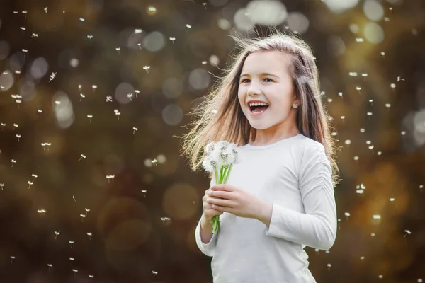 Niña oliendo un diente de león blanco en el parque de otoño — Foto de Stock