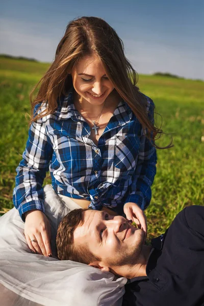 Man and woman sitting on the grass. his head in her lap — Stock Photo, Image