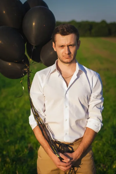 Ο τύπος σε λευκό πουκάμισο με μαύρο μπαλόνια που στέκεται σε ένα πεδίο — Φωτογραφία Αρχείου