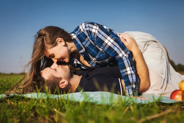 Paar liegt im Gras. Mädchen ganz oben auf dem Kerl. sie küsst ihn — Stockfoto