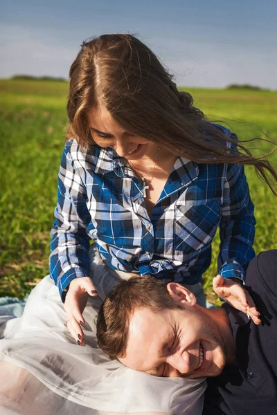 Jovem casal sentado na grama. menino colocar a cabeça para meninas joelhos — Fotografia de Stock