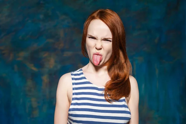 Подросток с рыжими волосами показывает язык. Гнев, агрессия и ненависть — стоковое фото