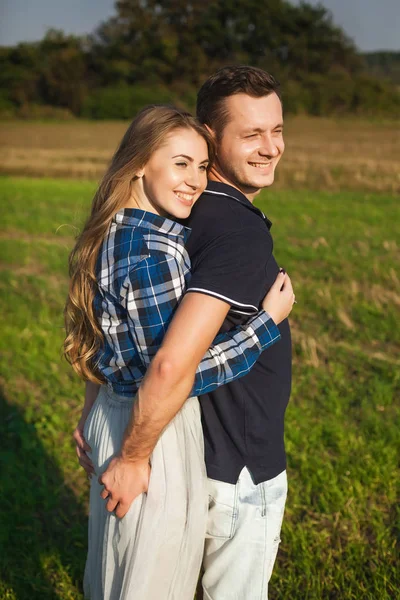 Casal amoroso e satisfeito abraçando em um campo — Fotografia de Stock