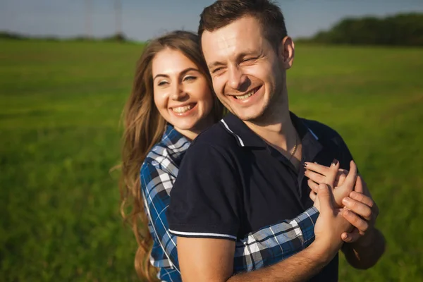 Šťastný a zamilovaný mládež objímat v poli — Stock fotografie