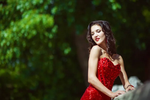 Сексуальна жінка з темним кучерявим довгим волоссям у червоній сукні — стокове фото