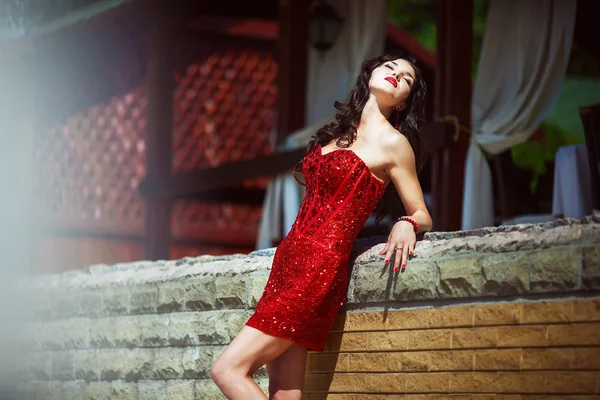 Stylish brunette in red dress on nature — Stock Photo, Image