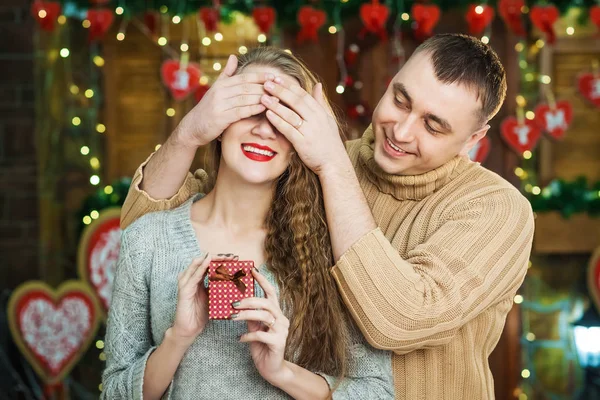 Man keeps his girlfriend eyes covered while she giving gift, romantic surprise for valentines day — Stock Photo, Image