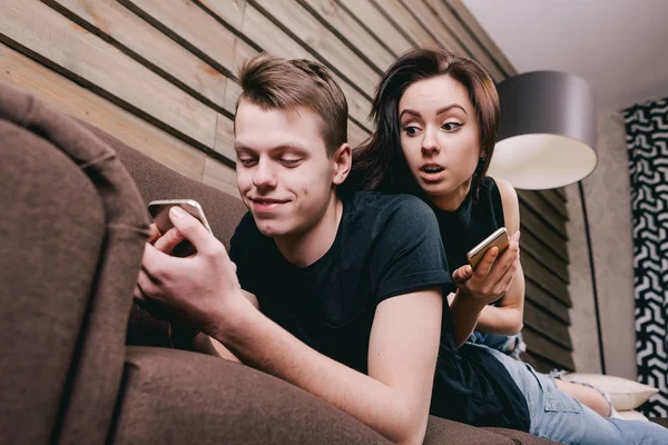 Pareja joven en la cama con smartphone en las manos — Foto de Stock