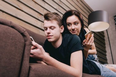 şirin çift yatakta elinde akıllı telefon ile