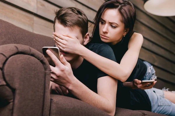 Молодая пара на диване с телефоном — стоковое фото