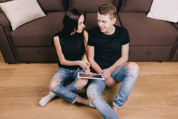 젊은 부부는 아파트 바닥에 앉아 태블릿 — 스톡 사진