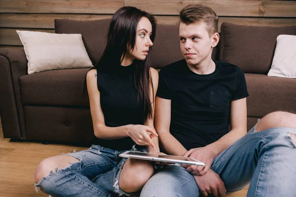 Feliz pareja en casa con la tableta sentada en el suelo — Foto de Stock