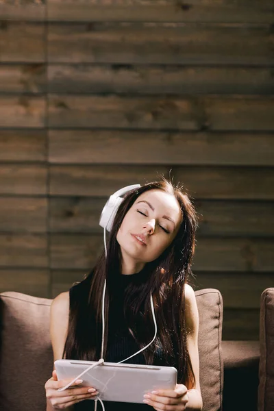 Брюнетка на диване слушает музыку с закрытыми глазами — стоковое фото