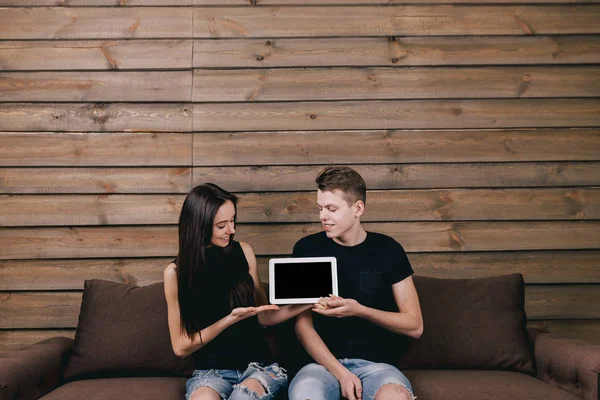 Пара сидит на диване с белым цифровым планшетом — стоковое фото