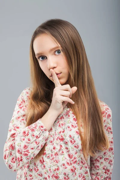 Girl looking at camera, holding finger on her lips — Stock Photo, Image