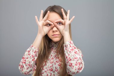 Neşeli sarışın kız parmaklarıyla gözlük yapma